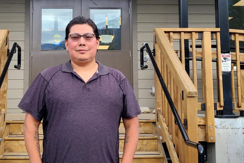 Photo of care aide Jordan Spinks standing in front of a set of wooden stairs