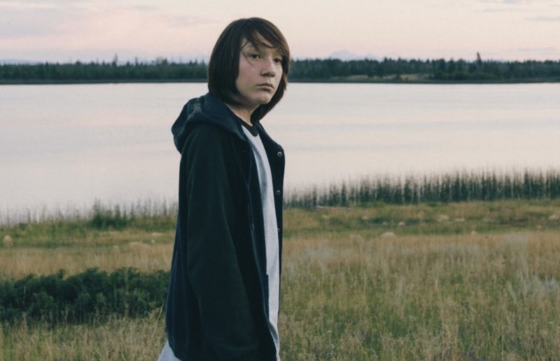 Actor William Lulua stands next to water in still from "Portraits from a Fire."