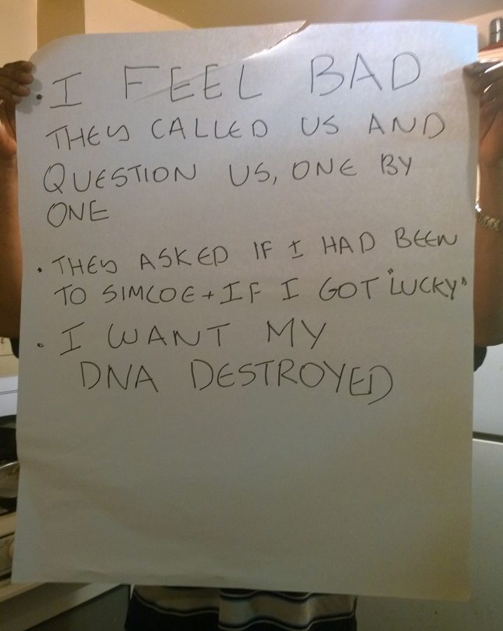 A migrant worker who had their DNA taken by the Ontario Provincial Police holds up a sign that reads, in full, "I feel bad. They called us and question us one by one. They asked if I had been to Simcoe and "got lucky." I want my DNA destroyed."