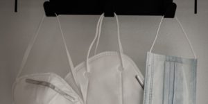 Three different medical masks hang on a hook. We aren't leaving this pandemic behind anytime soon.