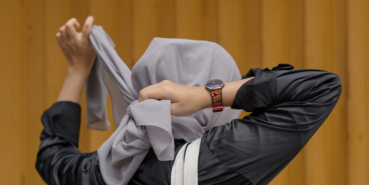 A woman tightens her hijab.