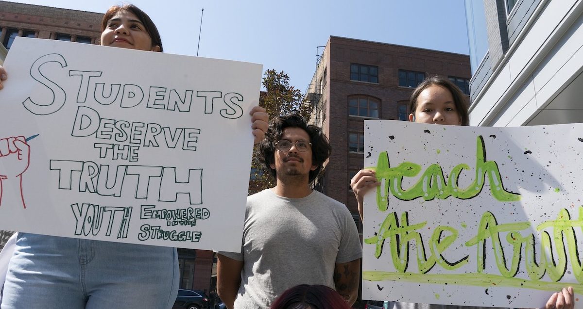 People hold signs at the Milwaukee Teach the Truth rally in June 2021.