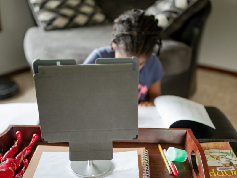 A young girl engages in distance learning from her living room on a tablet.