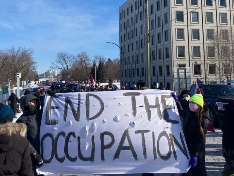 Photo of a blockade in Ottawa with an "End the Occupation" banner to stop more trucks joining the downtown convoy.