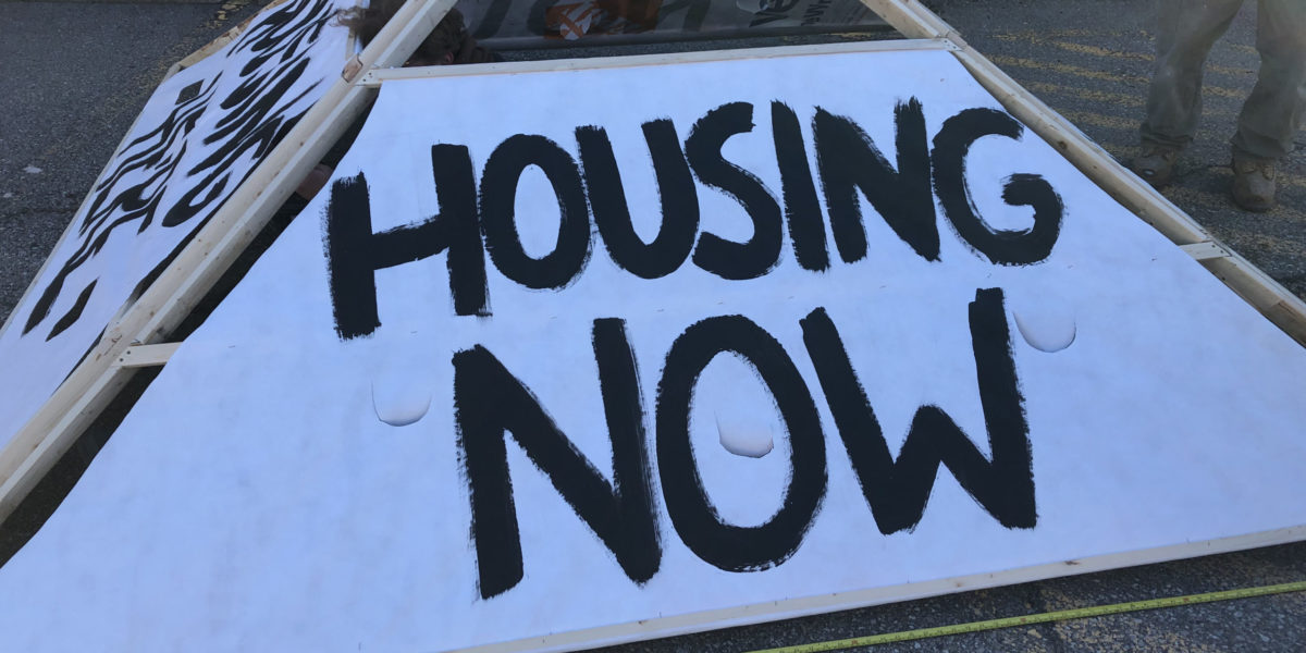 Photo of a sign which reads "Housing Now"