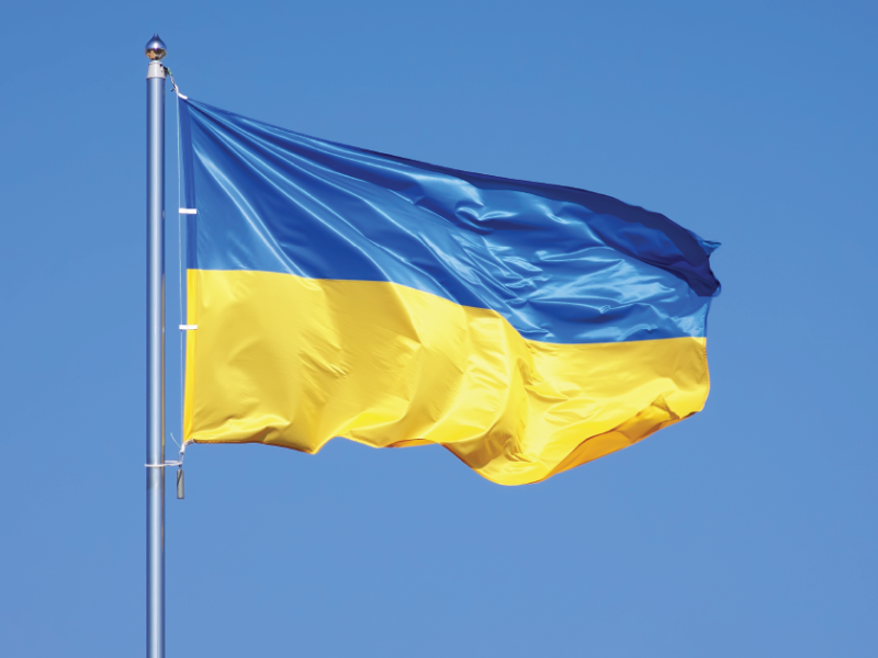 photo of the blue and yellow flag of Ukraine flying with blue sky behind it.