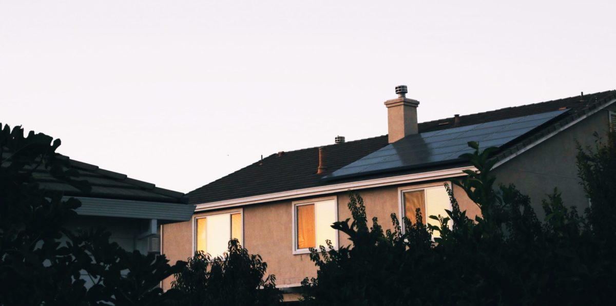 A photo of a house with a solar power panel on the rooftop.