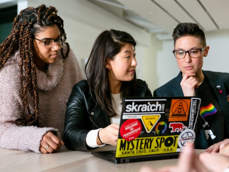 Photo of three students around a laptop.