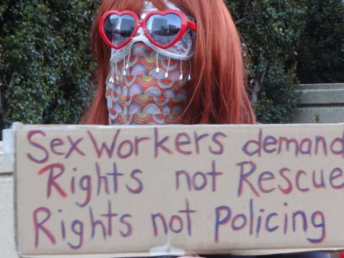 A sex worker marching on International Women's Day 2017, holding up a sign that calls for "Rights not Rescue, Rights not Policing."