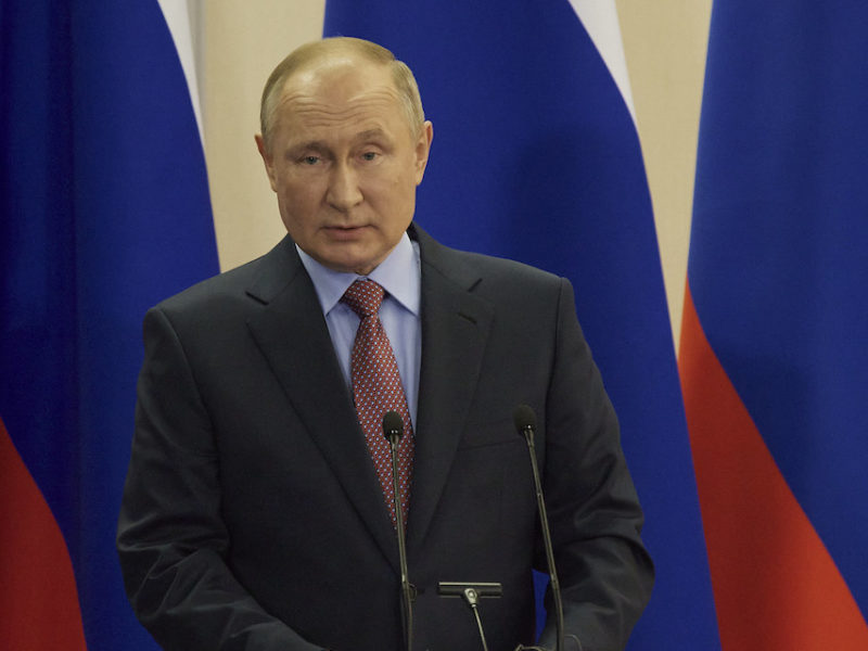 This photo shows Russian President Vladimir Putin stands at a podium in front of the Russian flag.