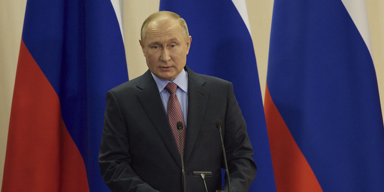This photo shows Russian President Vladimir Putin stands at a podium in front of the Russian flag.