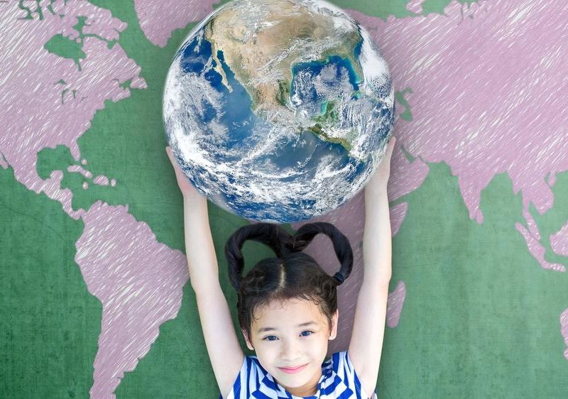 Photo of a young girl holding up a model of the planet earth..