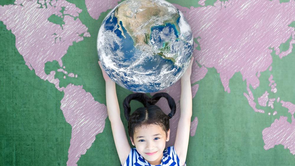 Photo of a young girl holding up a model of the planet earth..