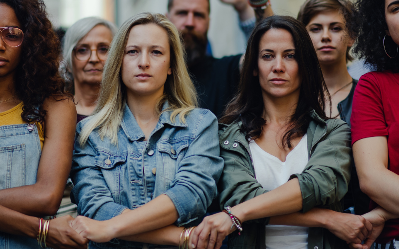 Photo of a group of women and men standing arm and arm