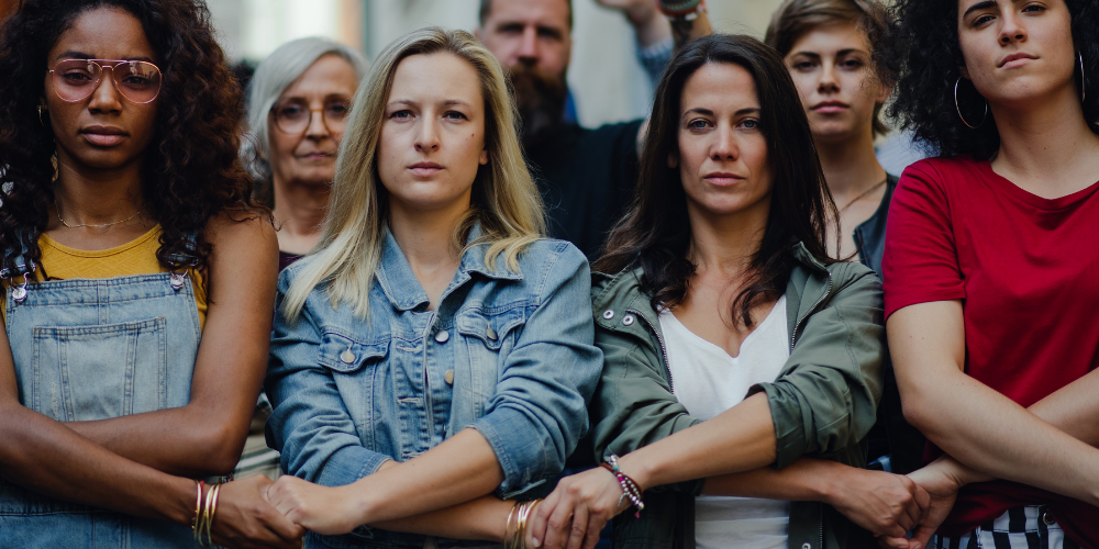 Photo of a group of women and men standing arm and arm