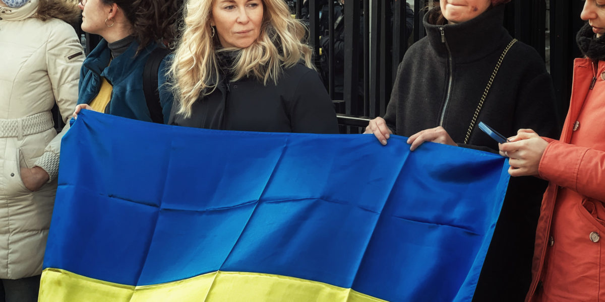 Photo of protestors holding up a Ukrainian flag.