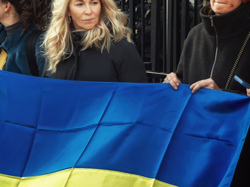 Photo of protestors holding up a Ukrainian flag.