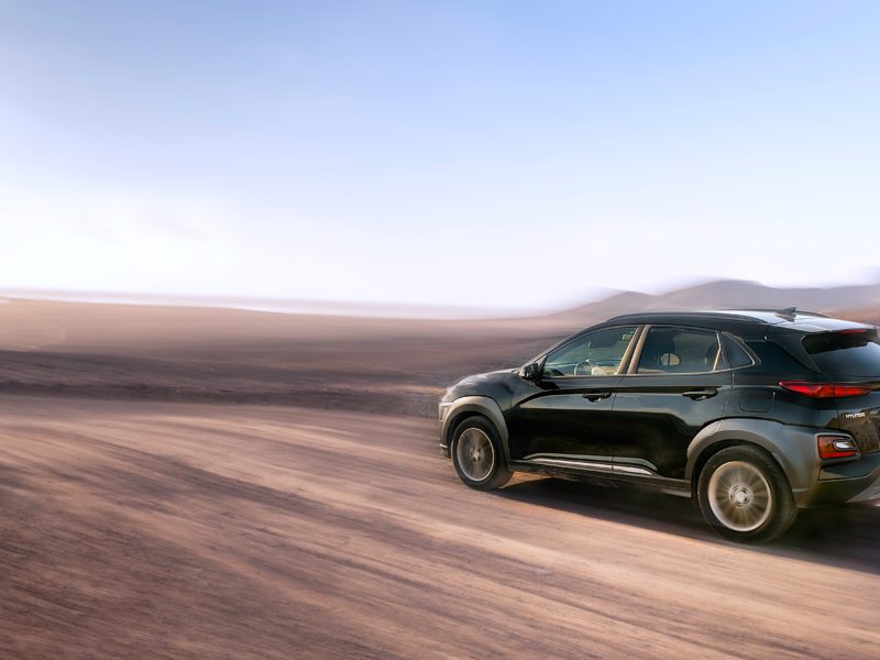 An SUV driving down an unpaved road.