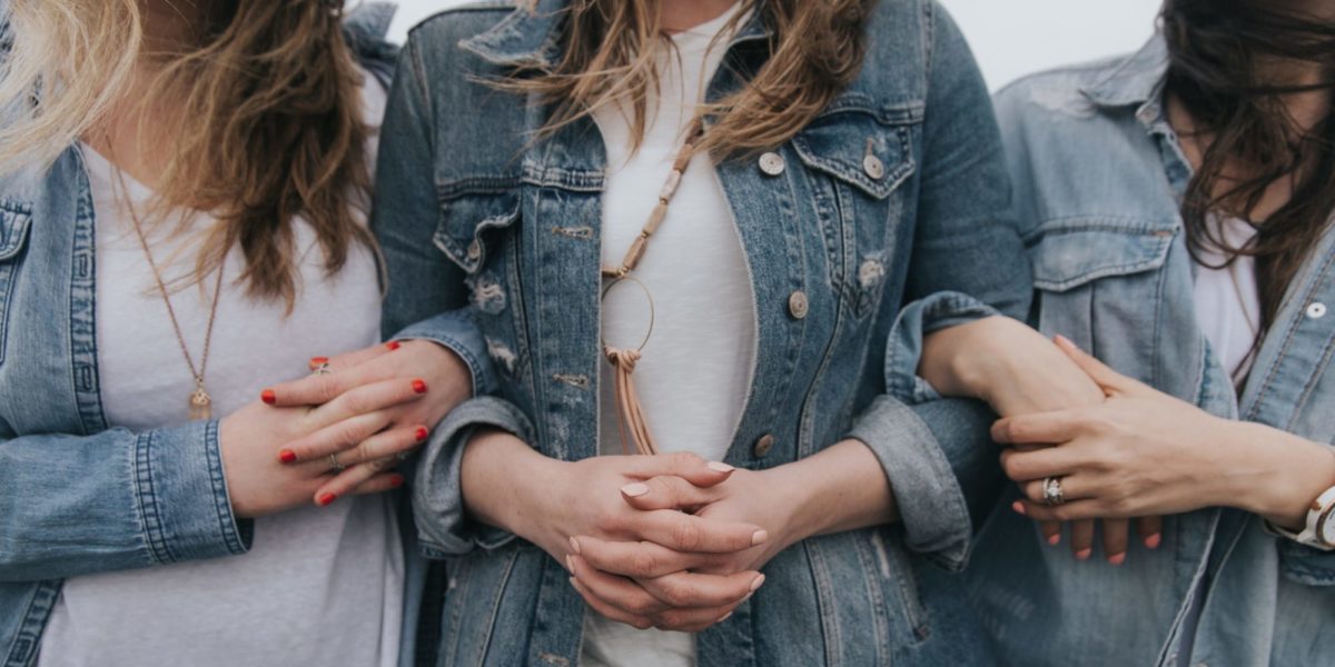 Photo of three women linking arms.