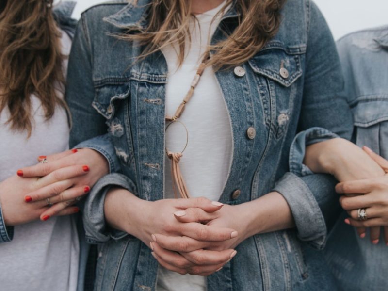 Photo of three women linking arms.