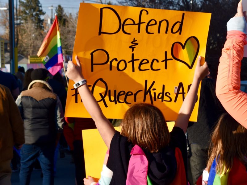 Photo of people holding up signs and walking in the streets at Pride Calgary.