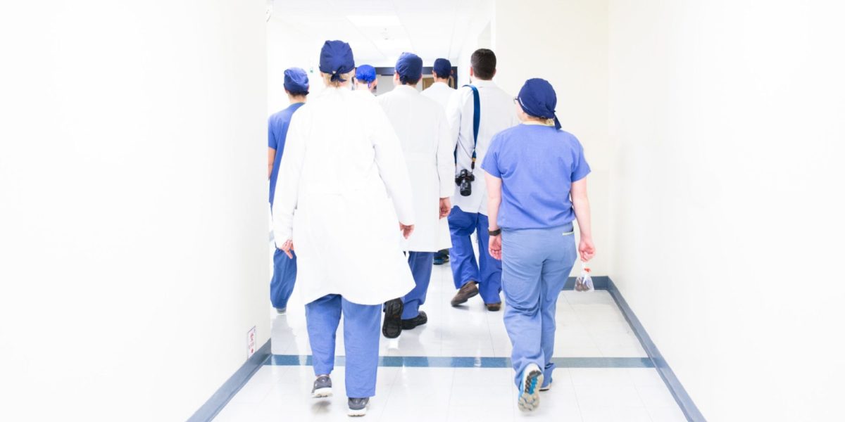 Photo of a group of doctors and nurses walking down a hallway in a hospital.