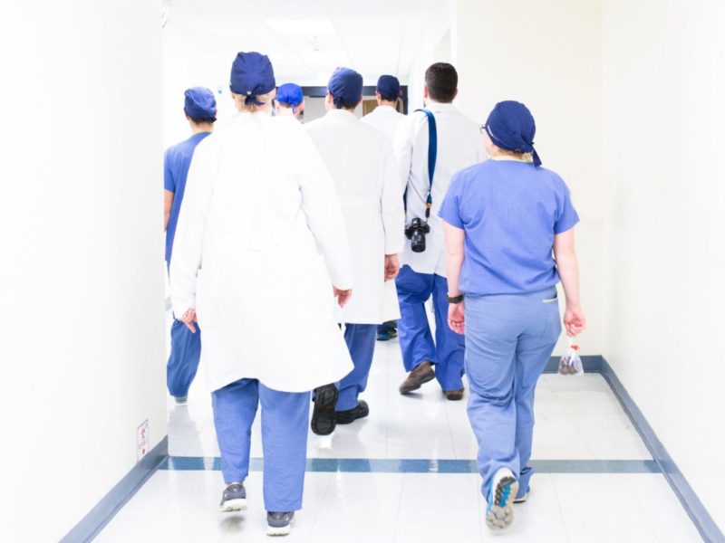 Photo of a group of doctors and nurses walking down a hallway in a hospital.