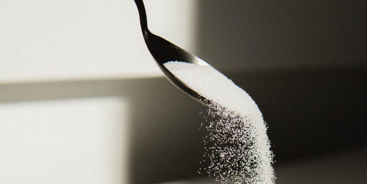 Photo of white sugar being poured from a spoon into a bowl