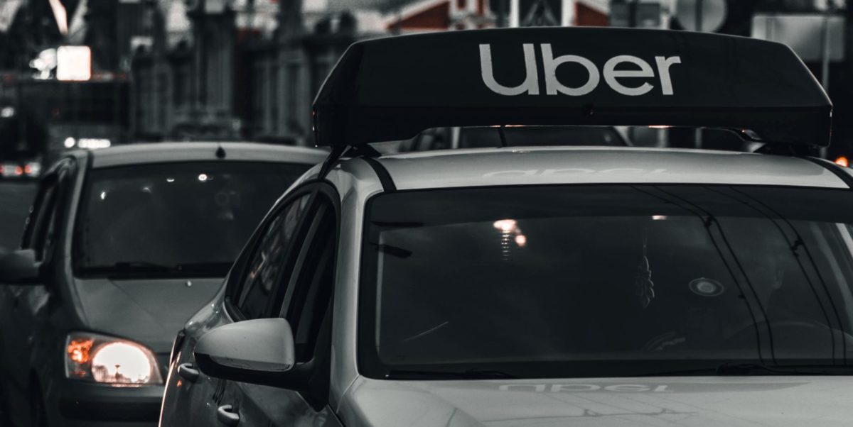 A black and white photo of an Uber car service in traffic.