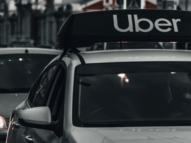 A black and white photo of an Uber car service in traffic.