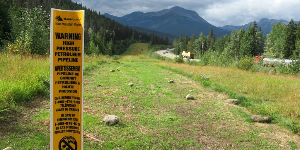 A photo of a sign warning of high pressure oil passing through the TransMountain pipeline. On Earth Day, Rita Wong is asking readers to consider ways of healing the land.