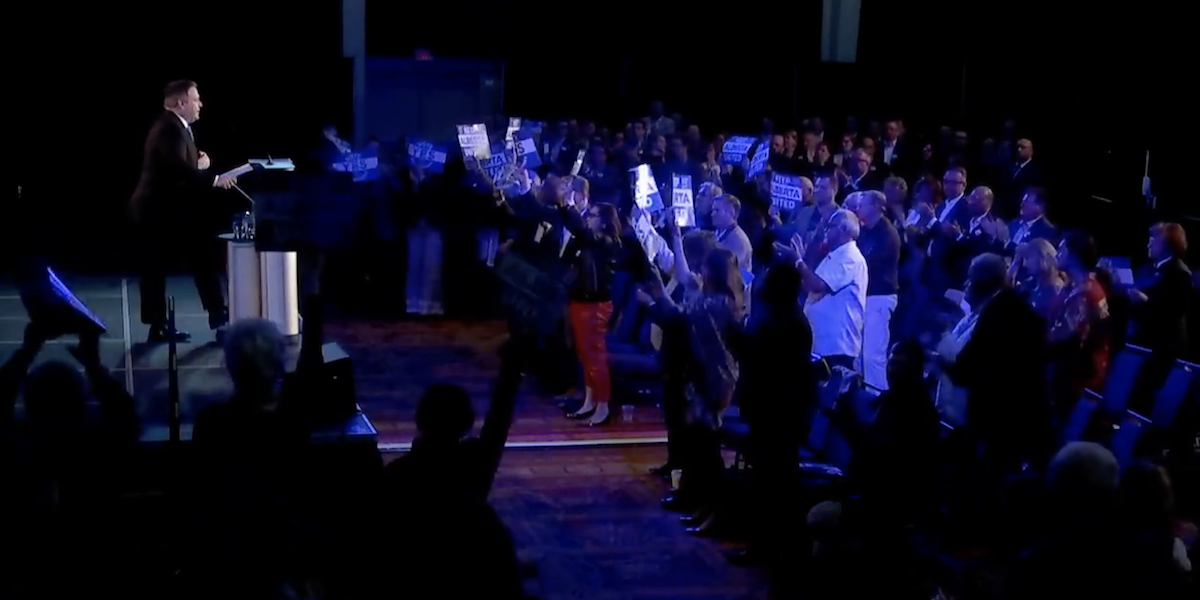 A screenshot of Alberta Premier Jason Kenney addresses a carefully curated crowd of about 100 supporters at yesterday’s UCP “Special General Meeting” in Red Deer. Kenney's leadership review has divided the party (Photo: Screenshot of United Conservative Party video).