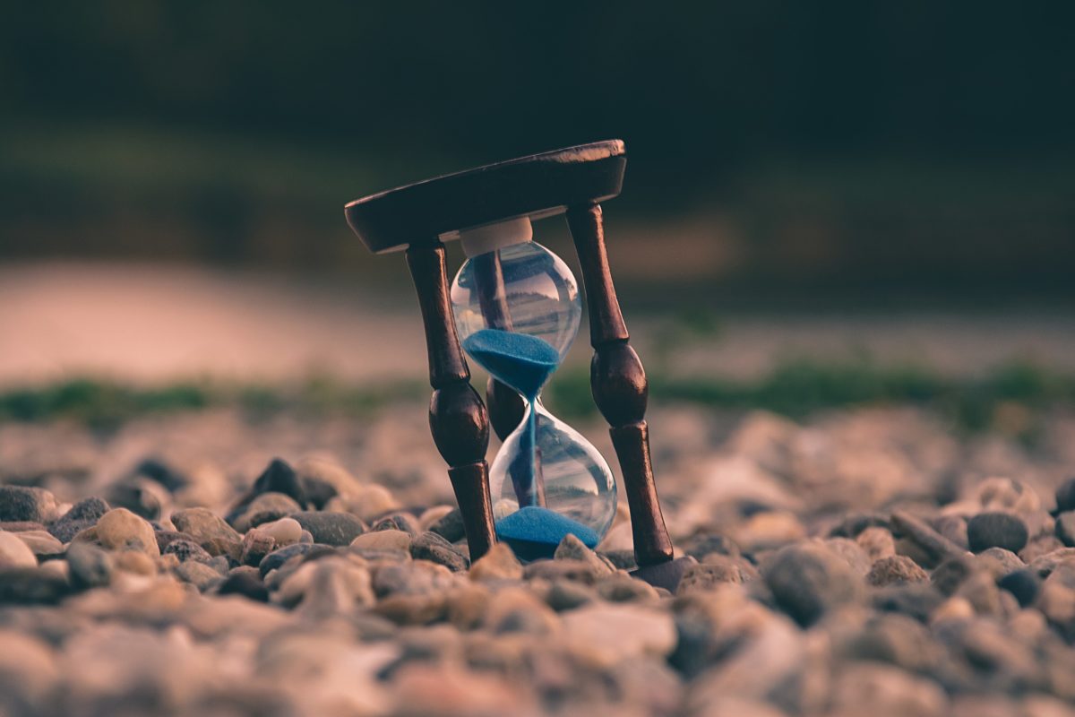 An hourglass resting on a pile of rocks.