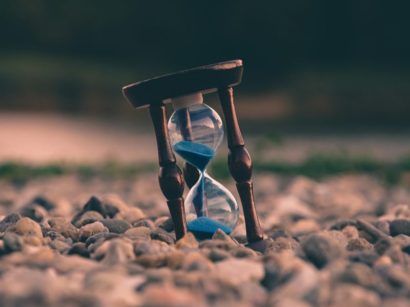 An hourglass resting on a pile of rocks.