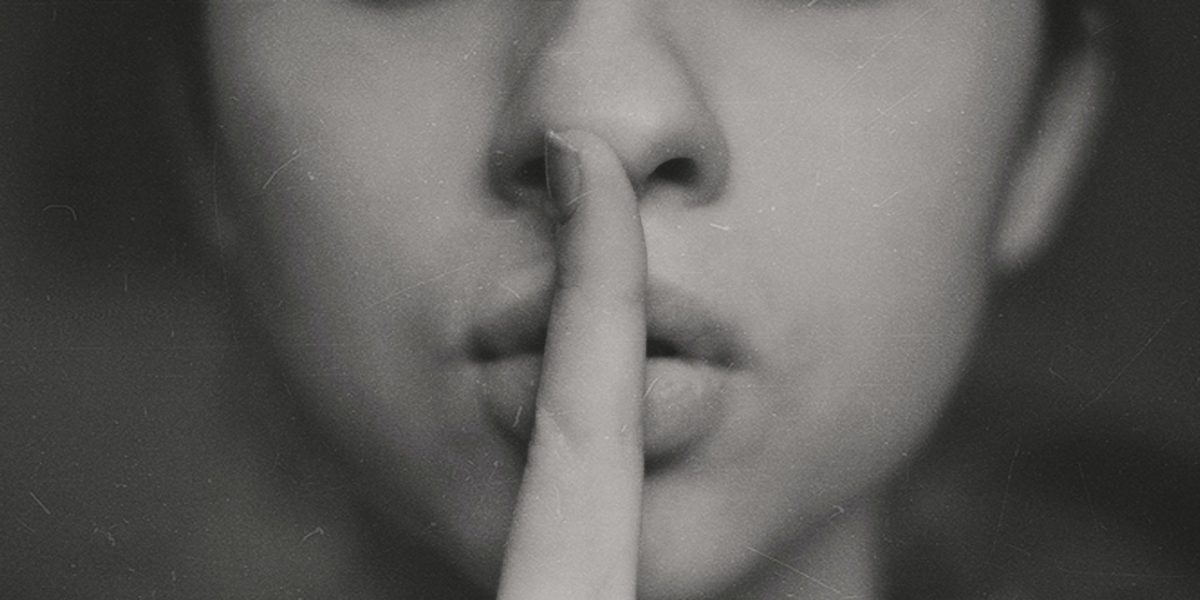 A photo of someone putting their finger to their lips, signifying silence.