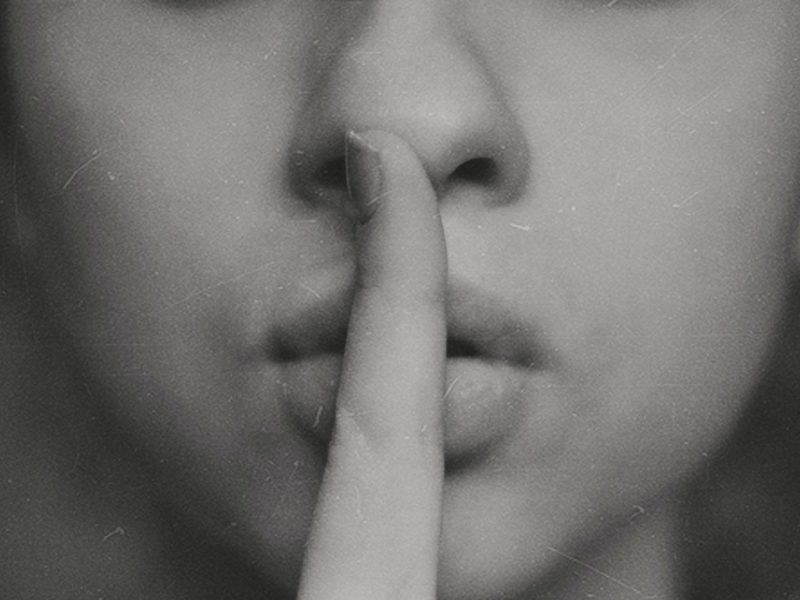 A photo of someone putting their finger to their lips, signifying silence.