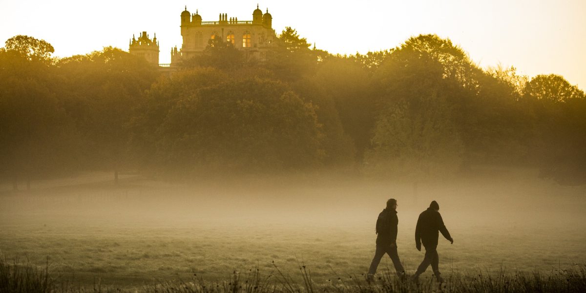 A photo of two individuals walking through the morning mist.