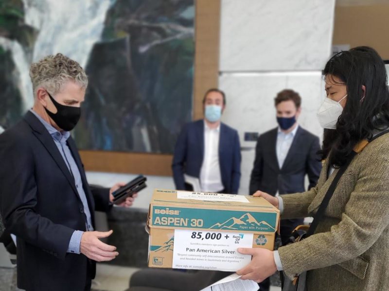 An woman tries to hand a box of petitions to a man wearing a suit at the Pan American Silver AGM on May 12, 2022