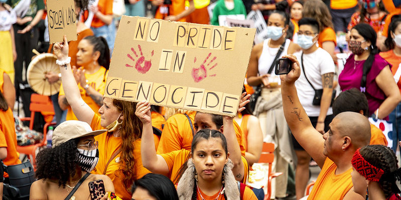 Photo of a group of protesters at the Cancel Canada Day Rally on July 1 , 2021 holding a sign which says "No pride in genocide."