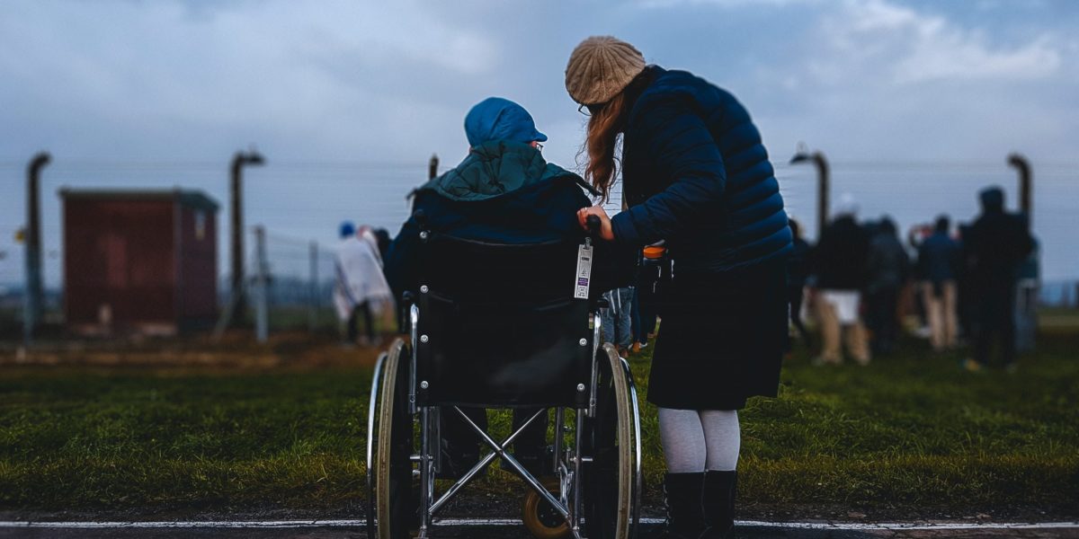 A photo of a person in a wheelchair and another person standing beside them