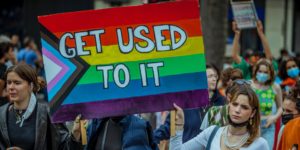 A sign with the LGBTQIA+ flag which says "Get used to it"