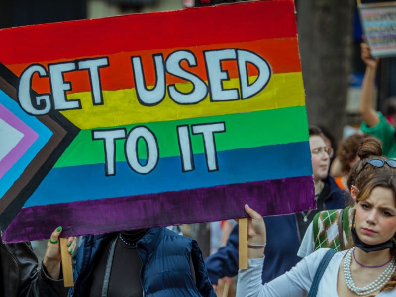 A sign with the LGBTQIA+ flag which says "Get used to it"