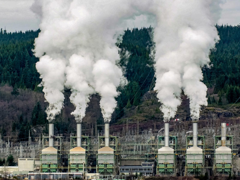 A photo of carbon emissions being released into the atmosphere from industrial smoke stacks.