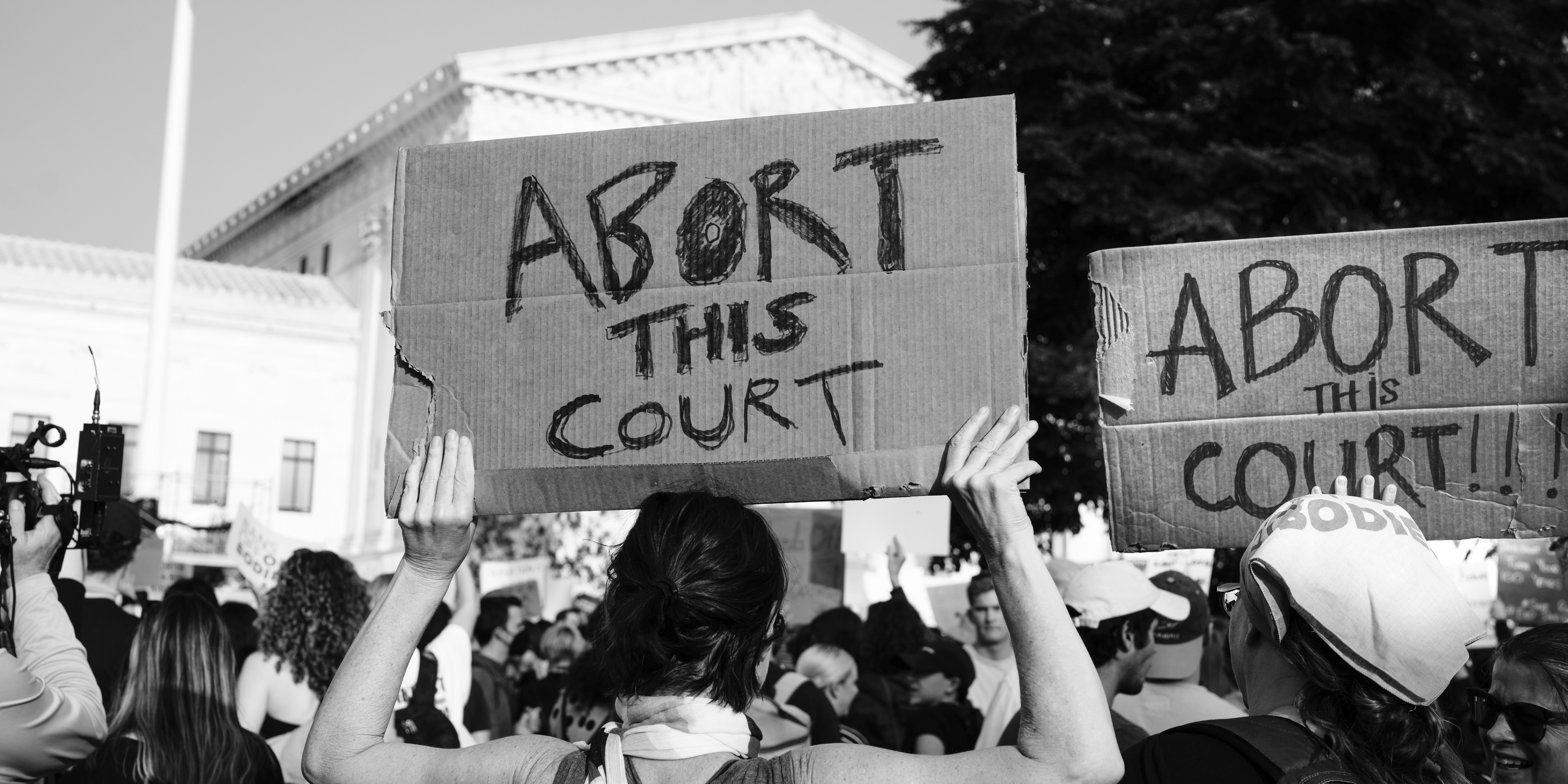 Protestor holding up sign 'abort this court' in front of the Sur