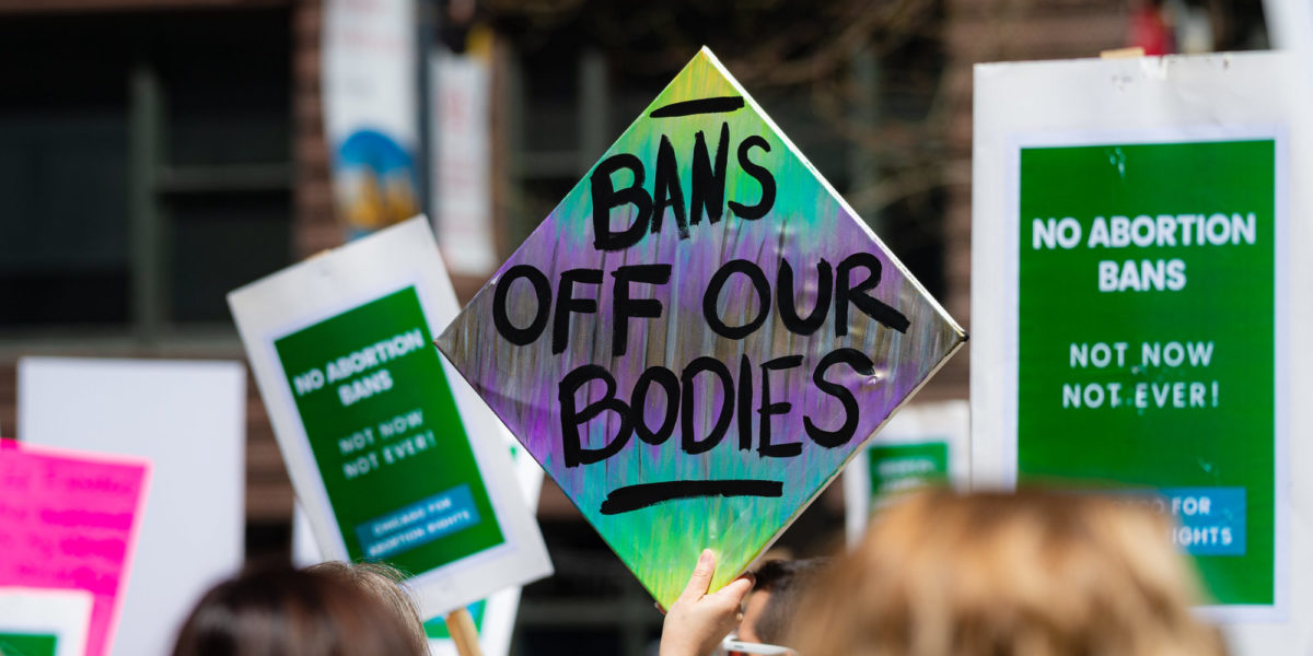 Colourful protest sign that says "Bans off our bodies"