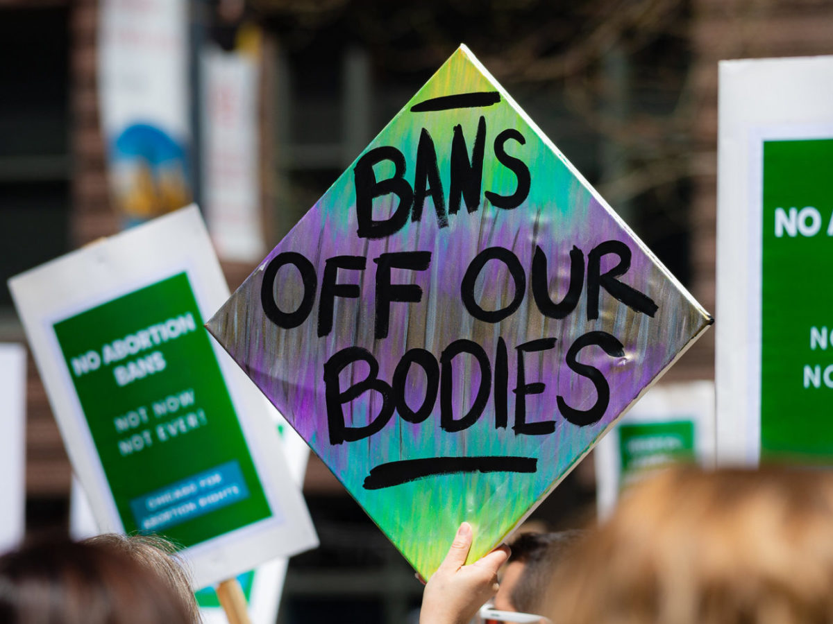 Colourful protest sign that says "Bans off our bodies"