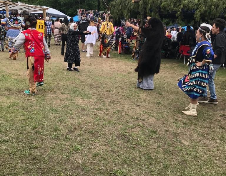 Attendees and dancers gathered in a Powwow circle.