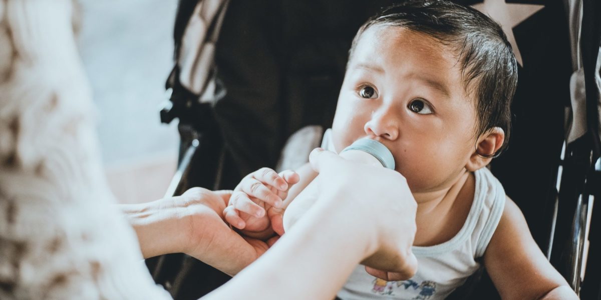 A photo of a baby drinking formula or milk from a baby bottle