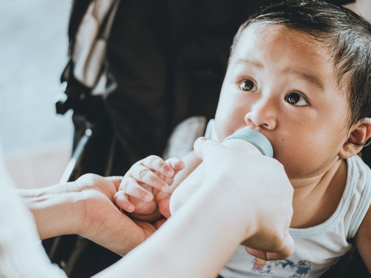 A photo of a baby drinking formula or milk from a baby bottle