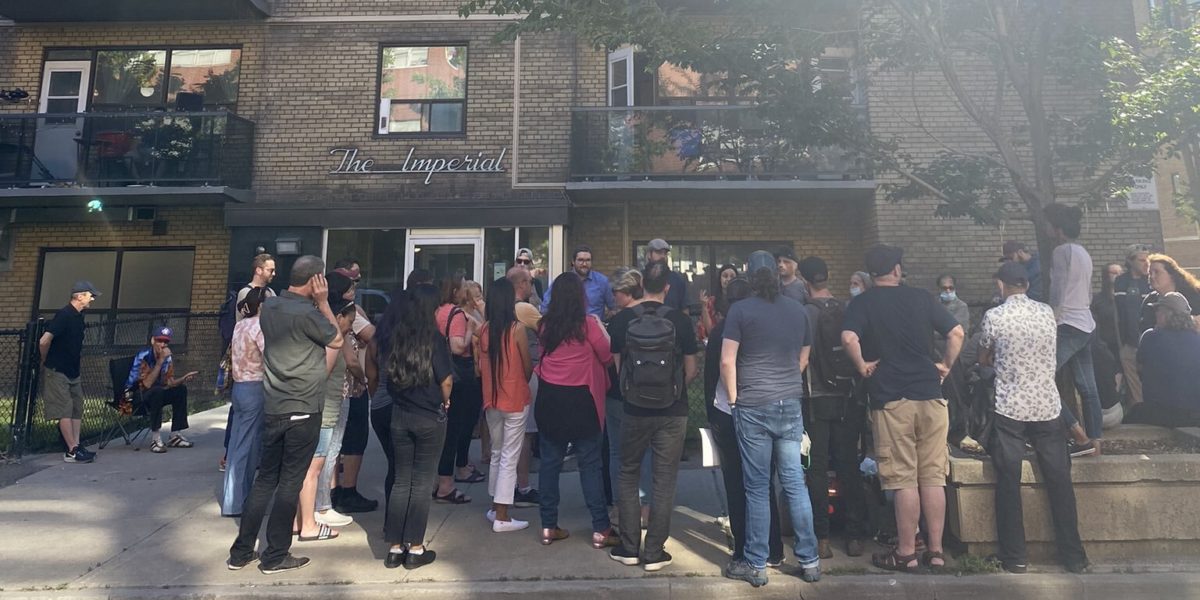 A photo of a group of people gathered outside an apartment building.